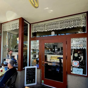 a woman sitting at a table in front of a coffee shop