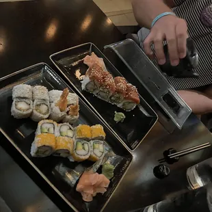 a person taking a picture of a plate of sushi