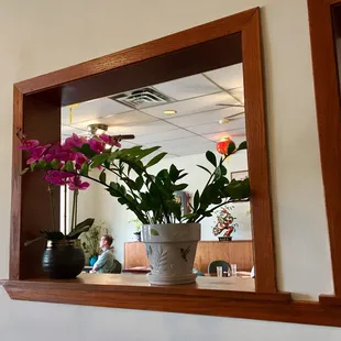 a vase of flowers in front of a mirror