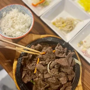 a bowl of beef with chopsticks