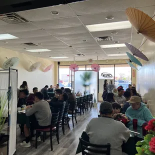 people sitting at tables with umbrellas hanging from the ceiling