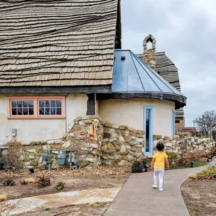 a little girl walking in front of a house