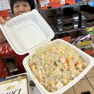 a woman holding a container of fried rice