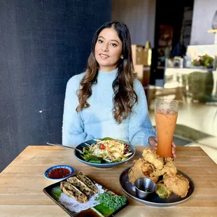 a woman sitting at a table with plates of food