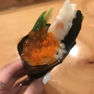 a person holding a piece of sushi