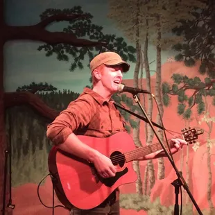 a man playing a guitar and singing into a microphone