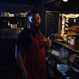 a man in a red apron holding a drink
