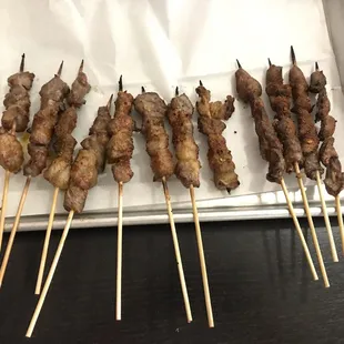 a tray of skewered meat on skewers