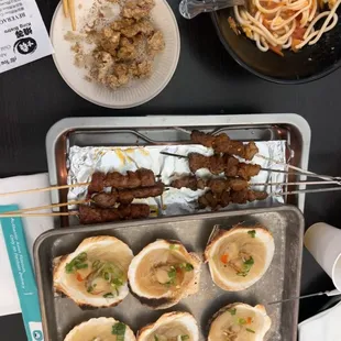 a tray of oysters and a tray of meat skewers