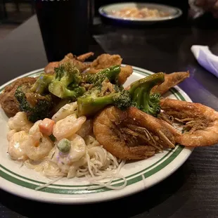 a plate of shrimp, broccoli, and noodles