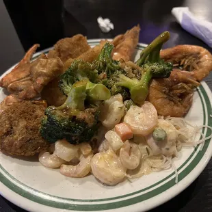 a plate of food with shrimp, broccoli, and noodles