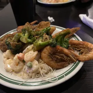 a plate of food with shrimp, broccoli and noodles