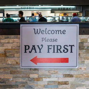 a pay first sign in front of a counter