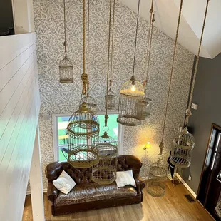 a living room with a leather couch and birdcages hanging from the ceiling
