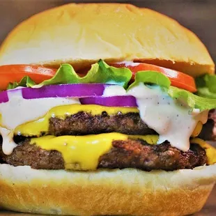 a hamburger with cheese, lettuce, tomato, onion, and lettuce