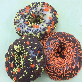 three chocolate donuts with sprinkles