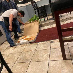 the man dropped his pizza and kind worker helping him