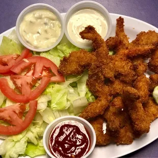 a plate of fried shrimp, lettuce, tomatoes, and sauces