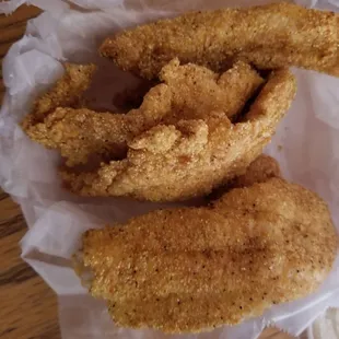 The hush puppies are under the fish.