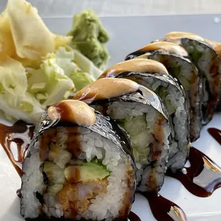 a plate of sushi with sauce and lettuce