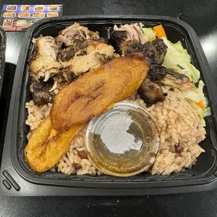 Jerk chicken (with side of sauce) with veggies, rice and plantains.
