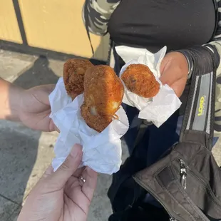 a woman holding two fried donuts