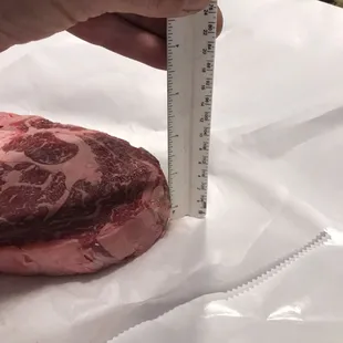 a person measuring a piece of meat
