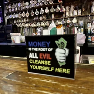 a sign that reads money is the root of all evil cleanse yourself here