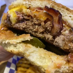 a hand holding a hamburger and french fries