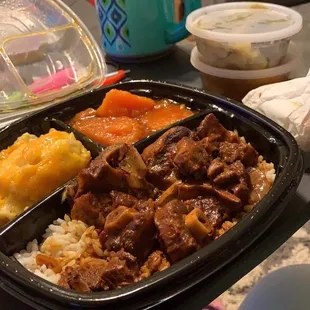 Oxtail meal over rice and gravy with Mac And Cheese and Candied Yams