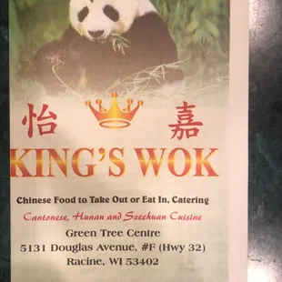 a panda eating grass in front of a sign