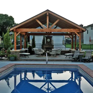 Raised paver patio with fireplace and pavilion.