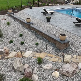 From a flagstone stairway, to river rock and plants , and  even a seat wall topped with fire-bowls, this landscape has it all!