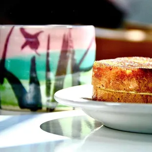 a piece of cake on a plate with a cup of coffee in the background