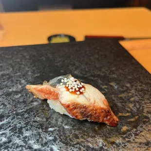 a piece of sushi on a slate plate