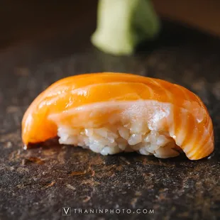 a piece of sushi with broccoli in the background
