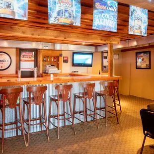 a bar with stools and a television