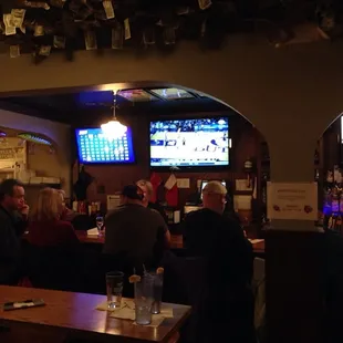 people sitting at a bar watching tvs