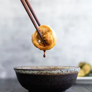 a person dipping a donut into a bowl