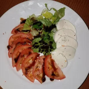 a plate of tomatoes, mozzarella, lettuce, and cheese