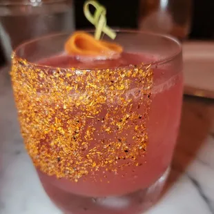 a pink drink with orange garnish
