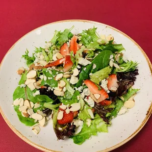 a plate of salad with strawberries and almonds