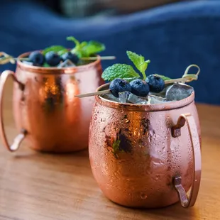 two copper mugs with blueberries and mint