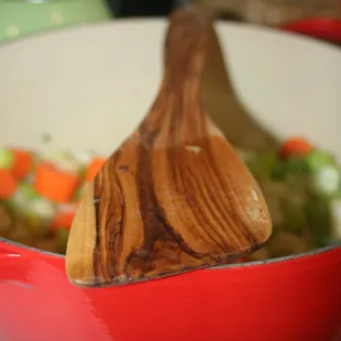 a wooden spoon in a pot of vegetables