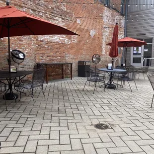 a brick patio with tables and umbrellas
