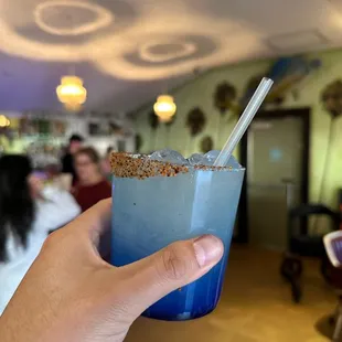 a hand holding a blue drink