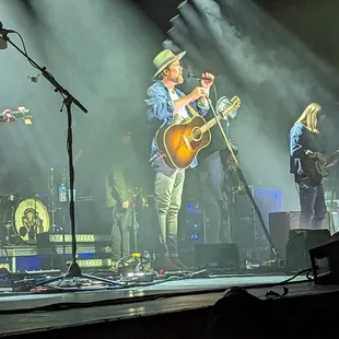 a man playing a guitar and singing into a microphone