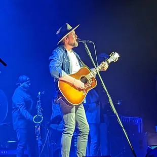a man playing a guitar and singing into a microphone