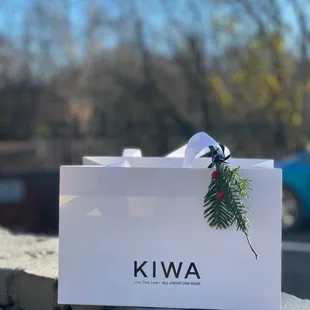a white gift bag with a pine branch on it