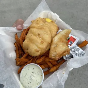 a person holding a basket of fish and fries